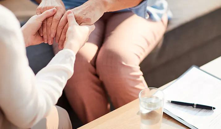 2 femmes assises se tenant la main pour représenter le soutien de l'association pour ces adhérents