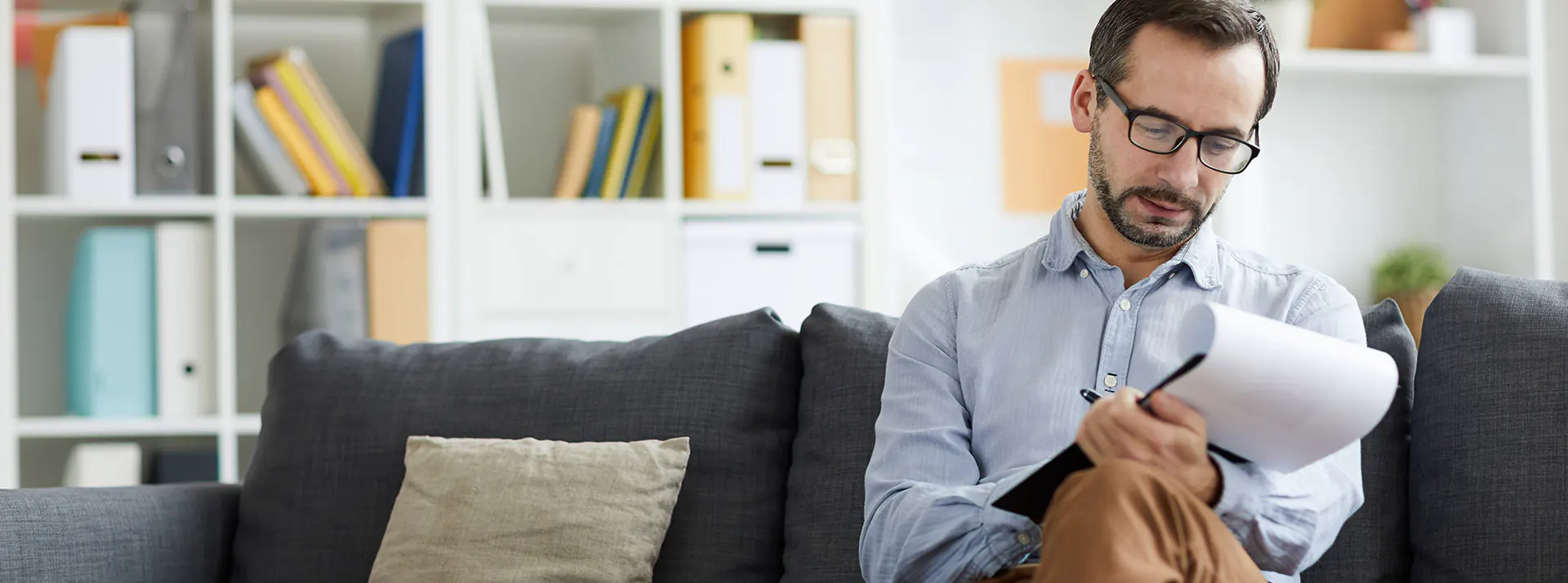 Un homme prenant des notes sur un calepin étant assis sur un divan